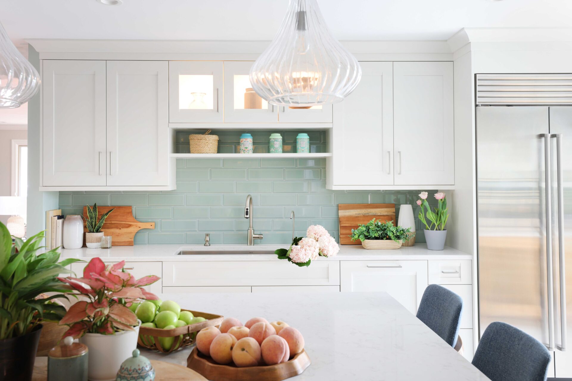 White kitchen cabinets with light green tile subway tile backsplash behind kitchen sink