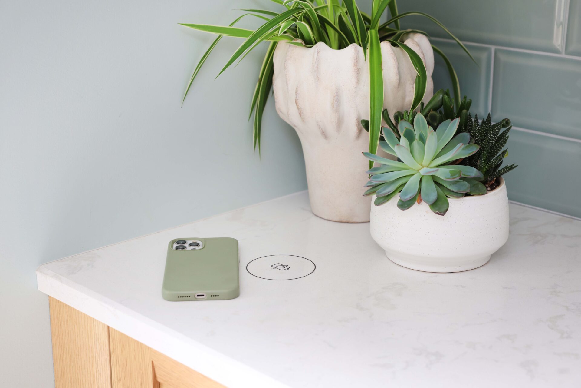 White countertop with phone charge surface, light green phone near charging circle
