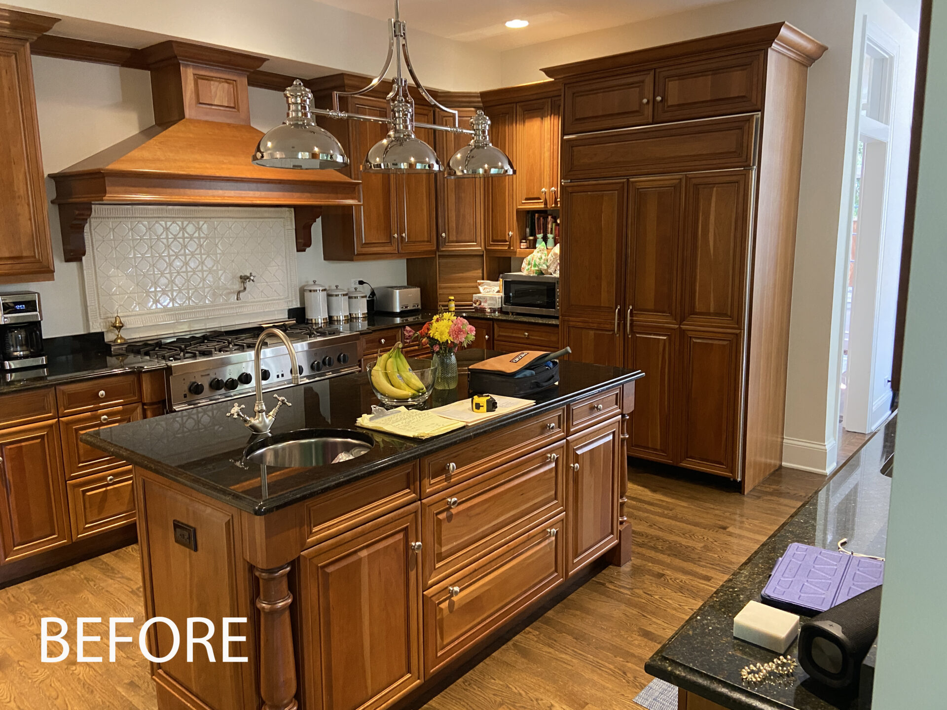 Before photo of cherry cabinets, black countertops