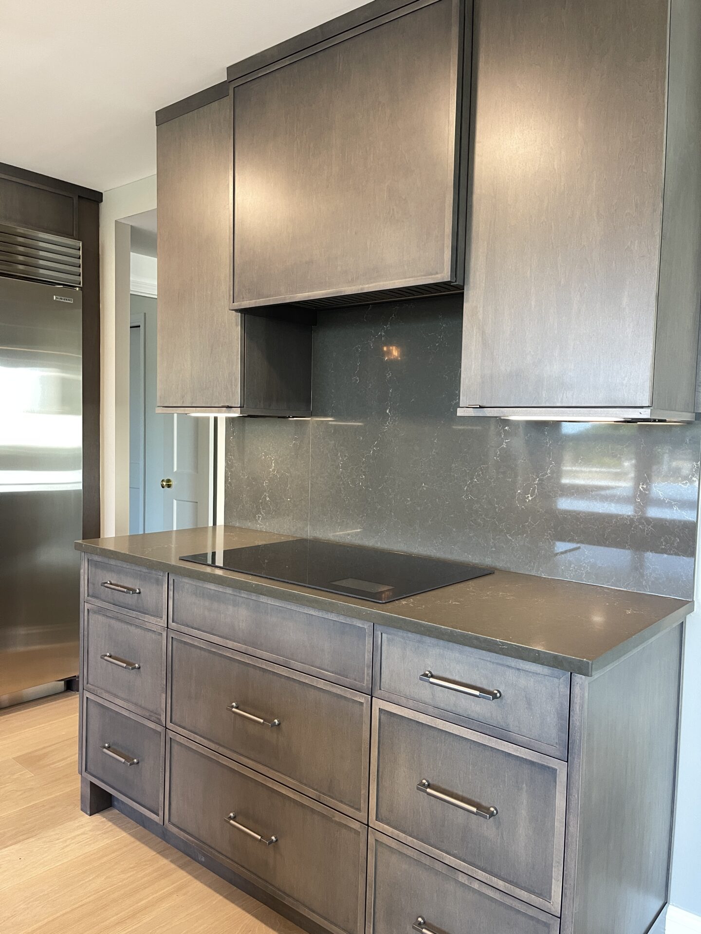 Dark brown maple range hood and matching surround cabinetry, and induction cooktop