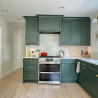 Forest green range hood and full height quartz backsplash, mid range shot