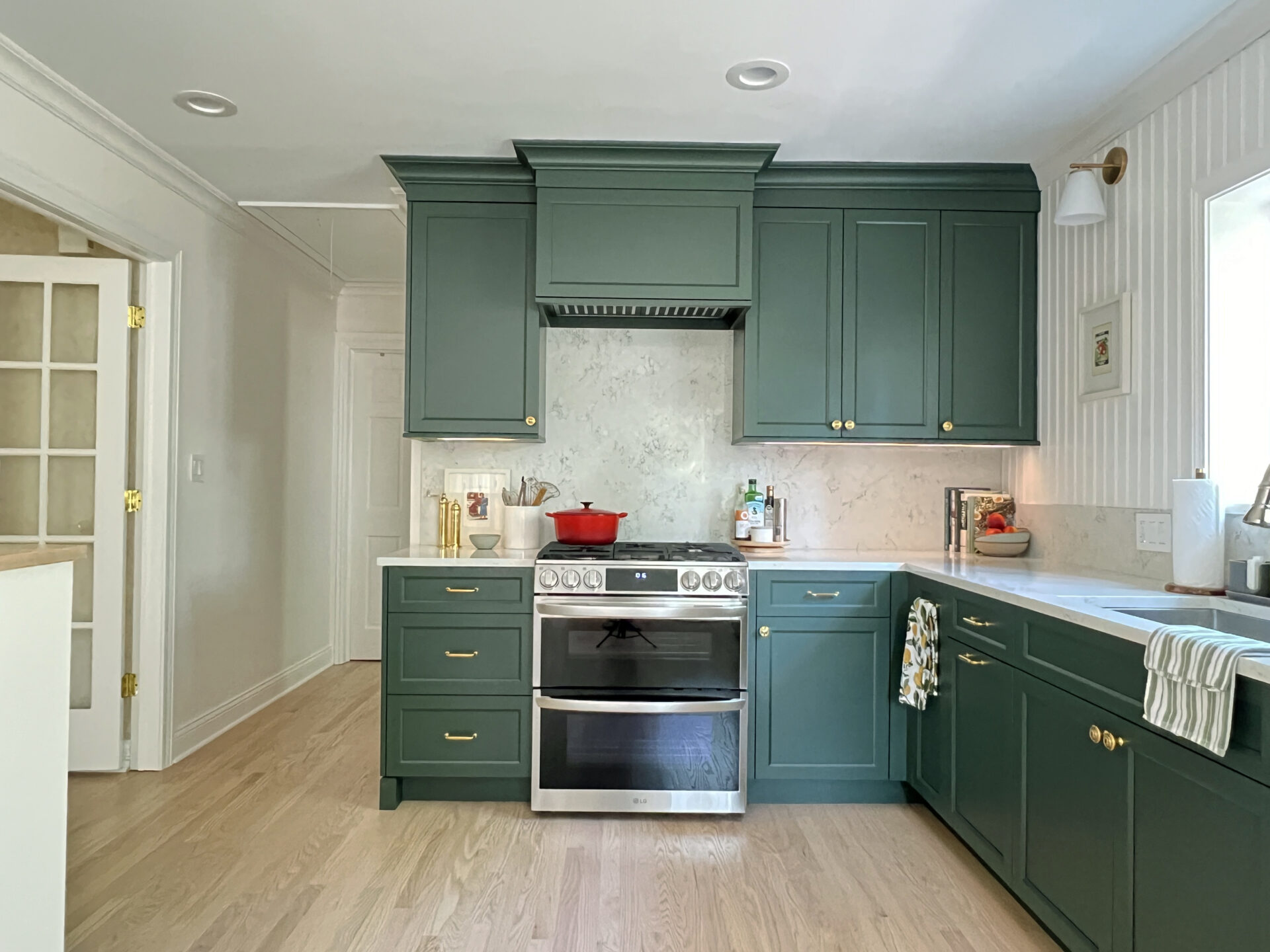 Forest green range hood and full height quartz backsplash, mid range shot