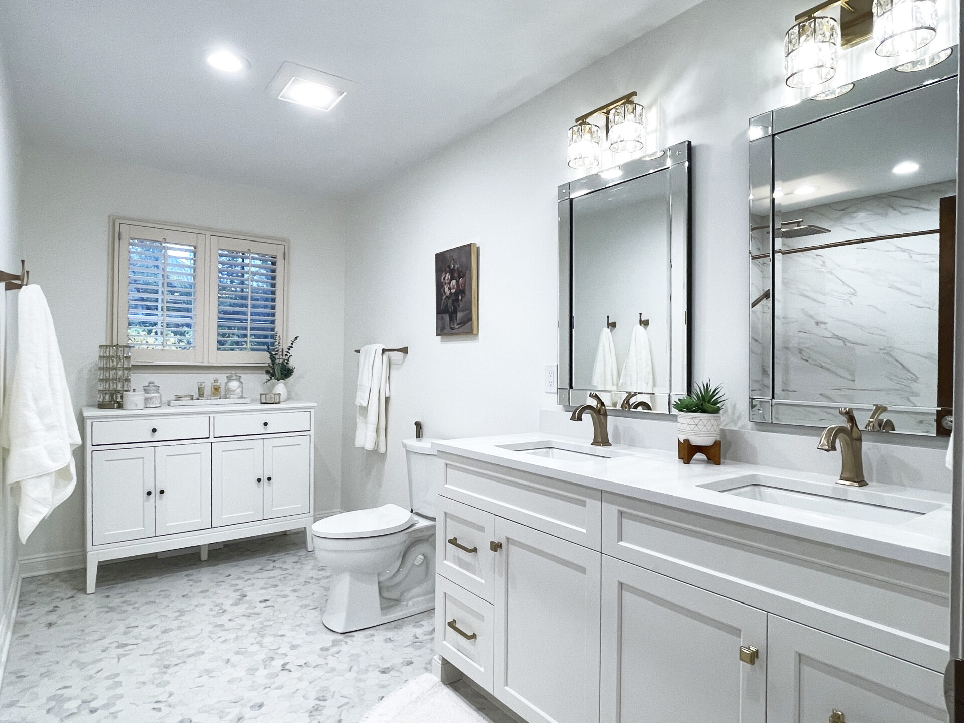White bathroom with white double vanity, toilet, additional freestanding white cabinet