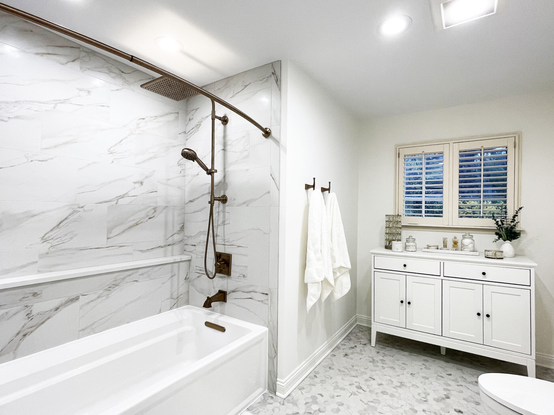 White bathroom with shower tub combo and large bathtub with handheld shower attachment and rain shower head