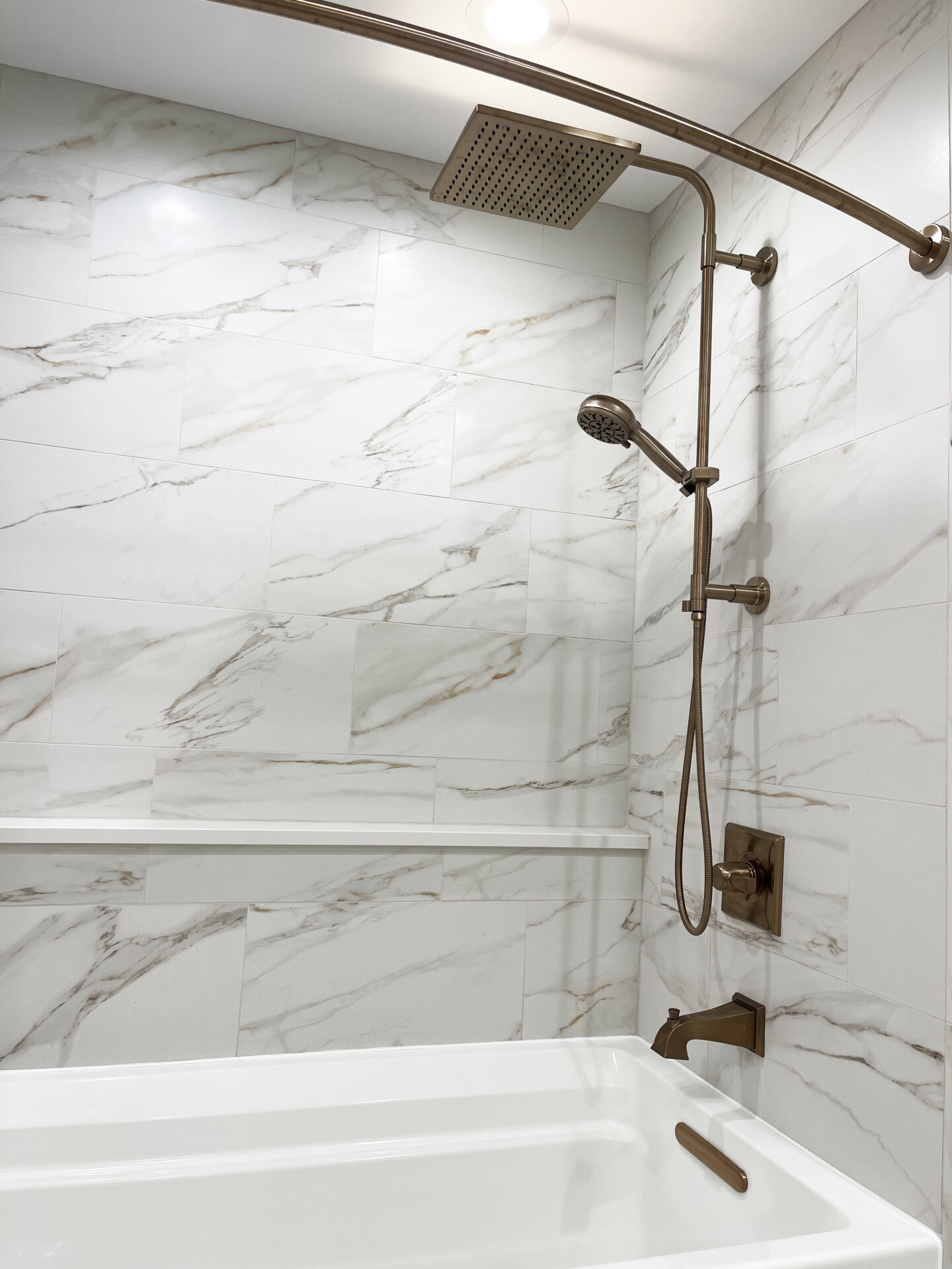 White bathroom with shower tub combo and large bathtub with handheld shower attachment and rain shower head