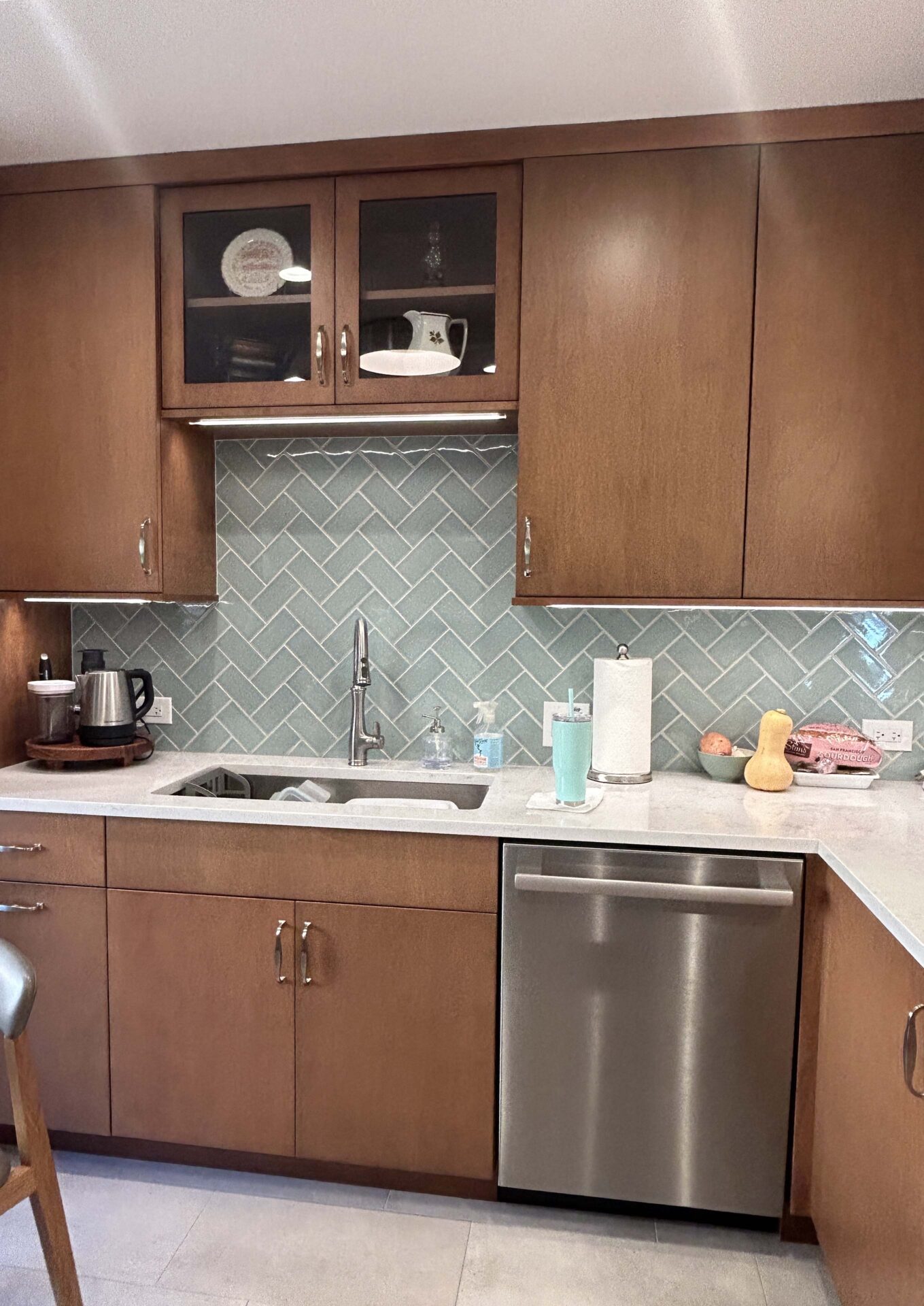 An "after" photo of a mid-century modern kitchen with a light blue herringbone backsplash