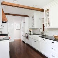 White Cabinetry with black countertops and wood beams on ceiling