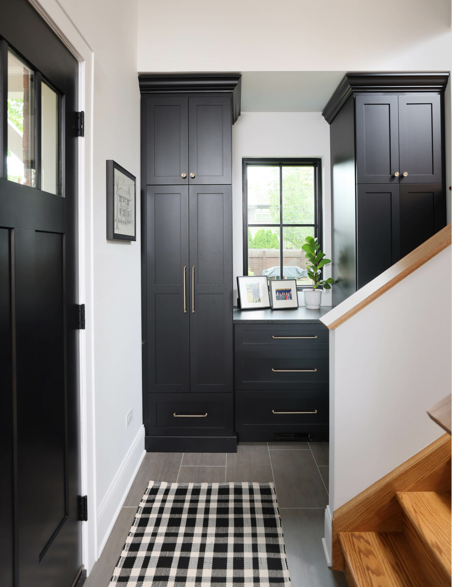 Black mudroom cabinets and landing zone at the bottom of the stairs
