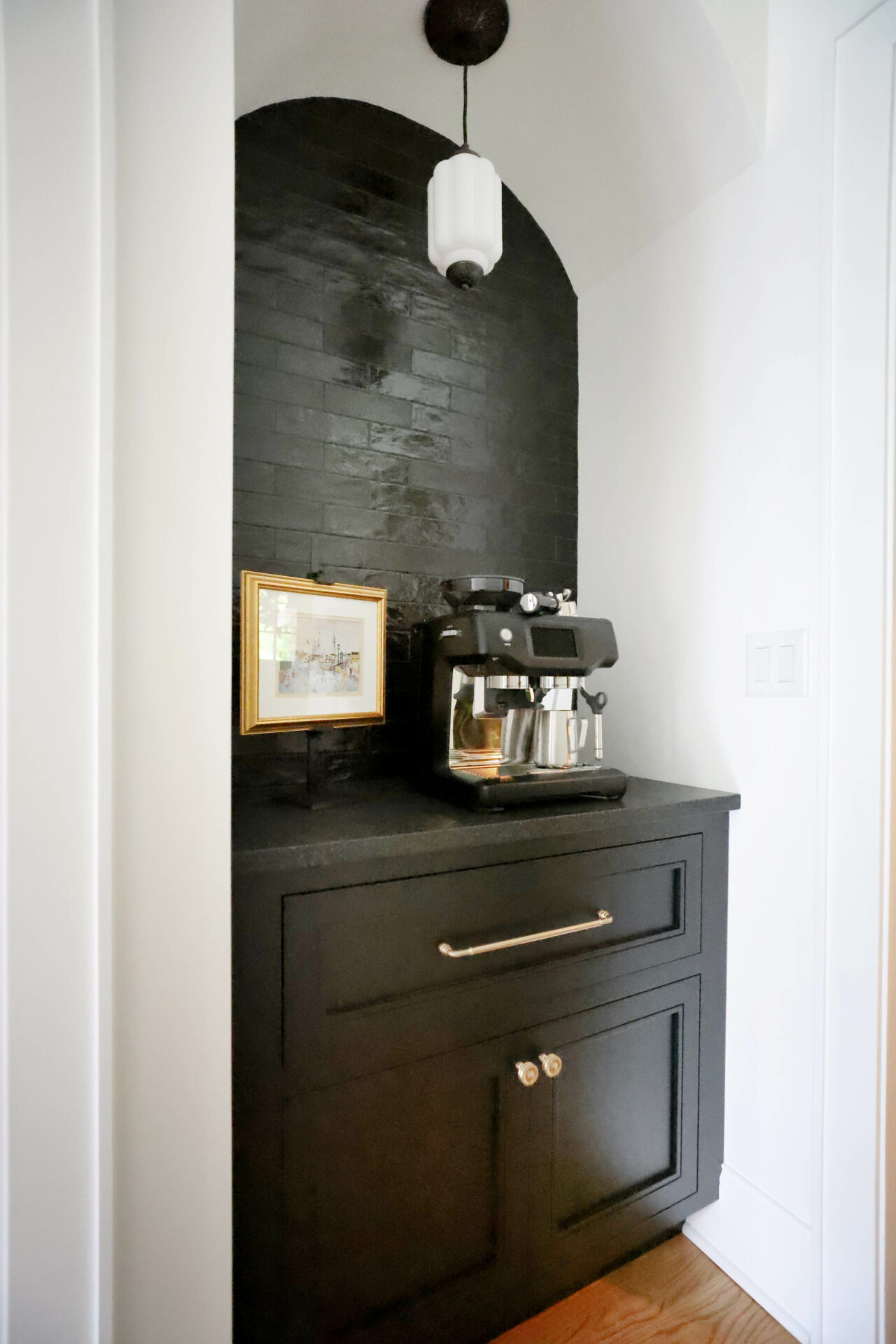 Black coffee bar in an arch top alcove near the kitchen accented with a black subway tile backsplash