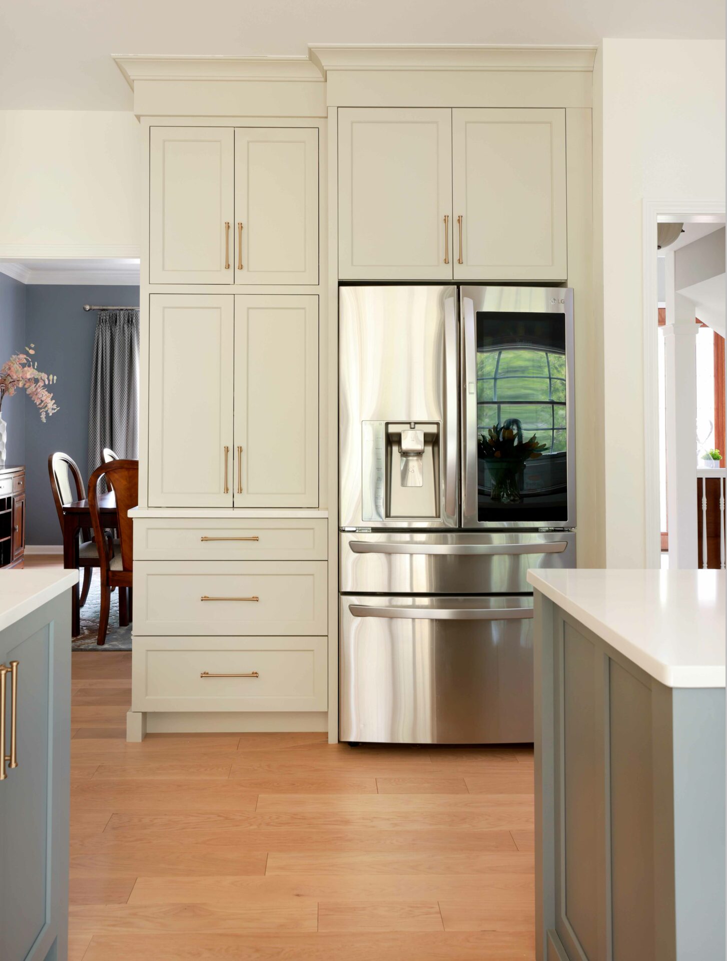 Warm white kitchen cabinets with stainless steel refrigerator