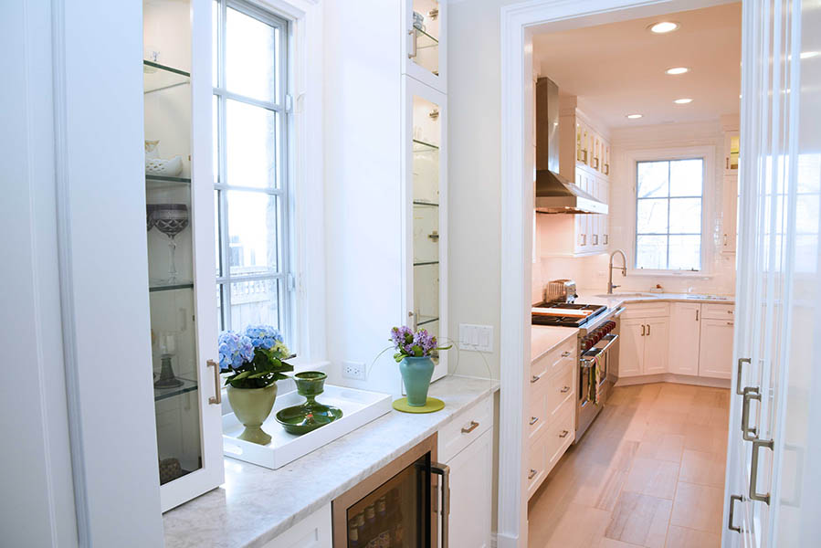 Glass front cabinets and marble countertops in a butler's pantry