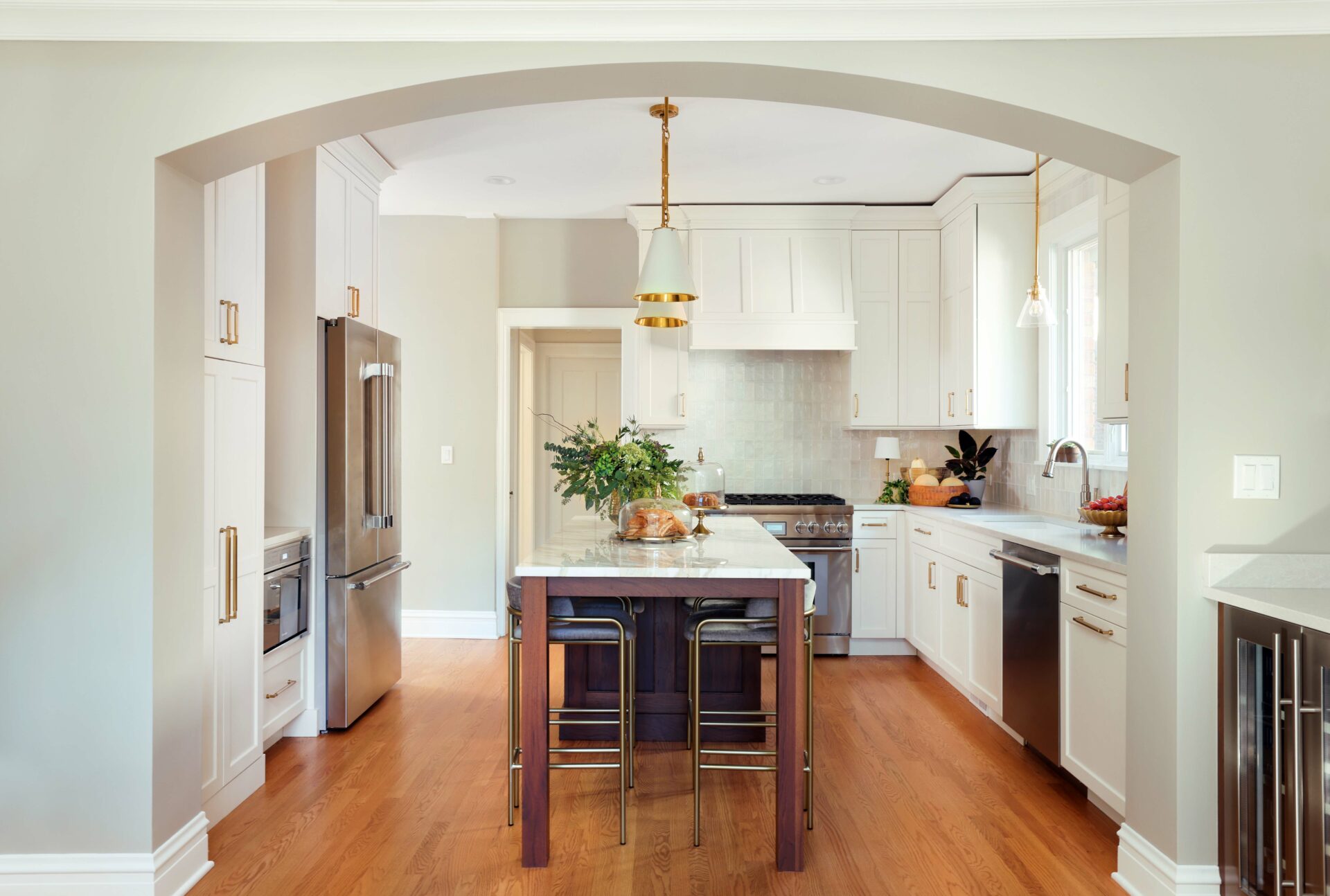 Arched doorway that leads to an ivory kitchen with a walnut island