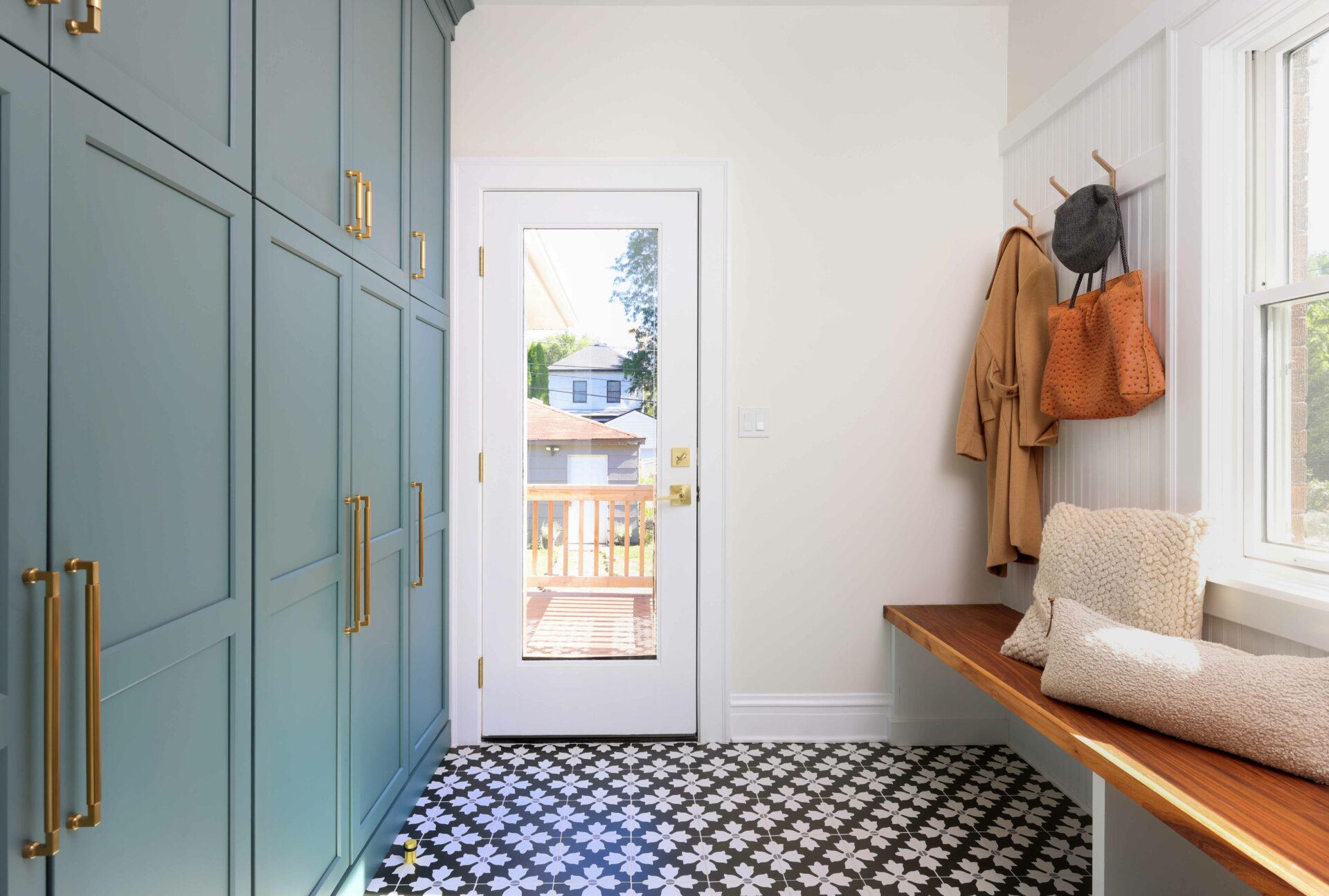 Blue Green mudroom cabinetry with patterned floor tile, beadboard walls, and stained oak bench