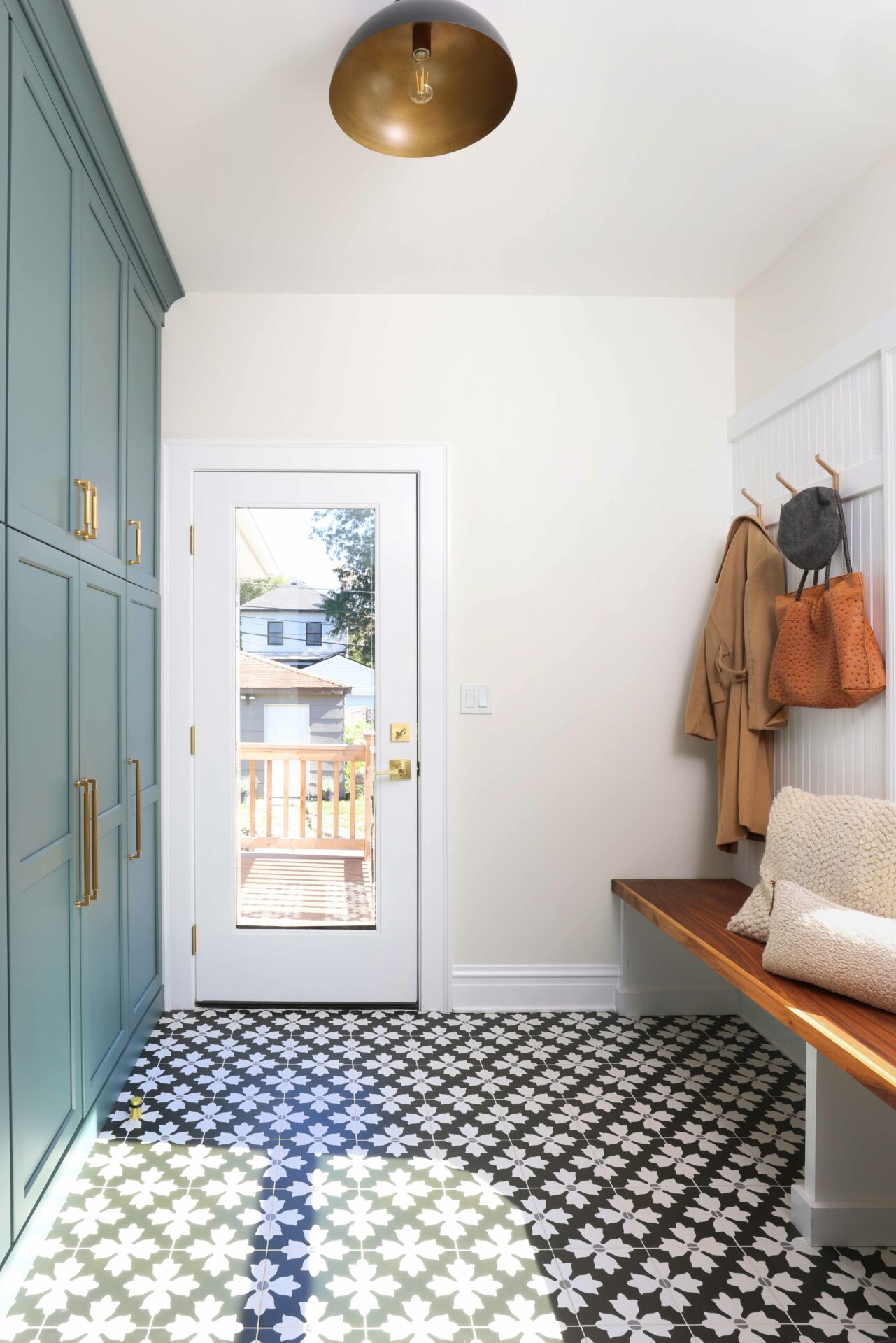Mudroom with blue - gray cabinetry, patterned floor tile and stained wooden bench