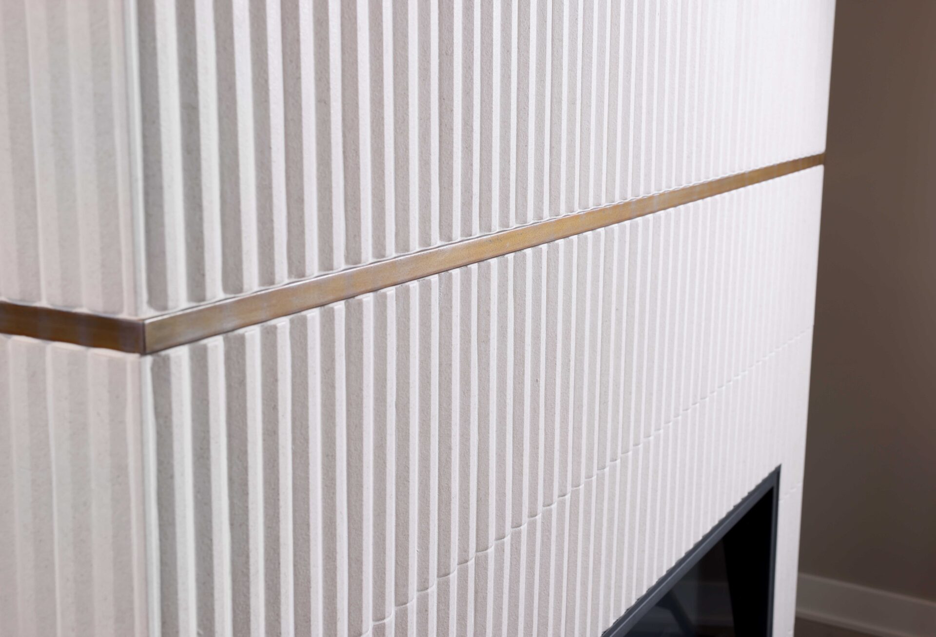 White fireplace surround with vertical tile and brass metal banding