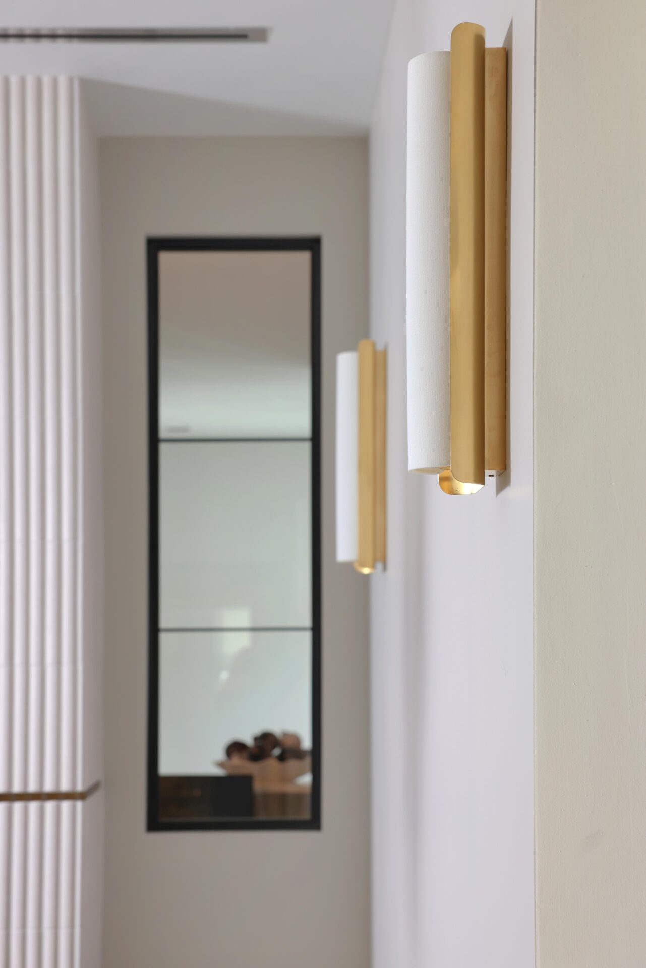 Vertical sconces, vertical tile and black frame window for good example of linear design