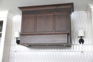 Cherry hood with ivory white beveled picket tile backsplash and sconces