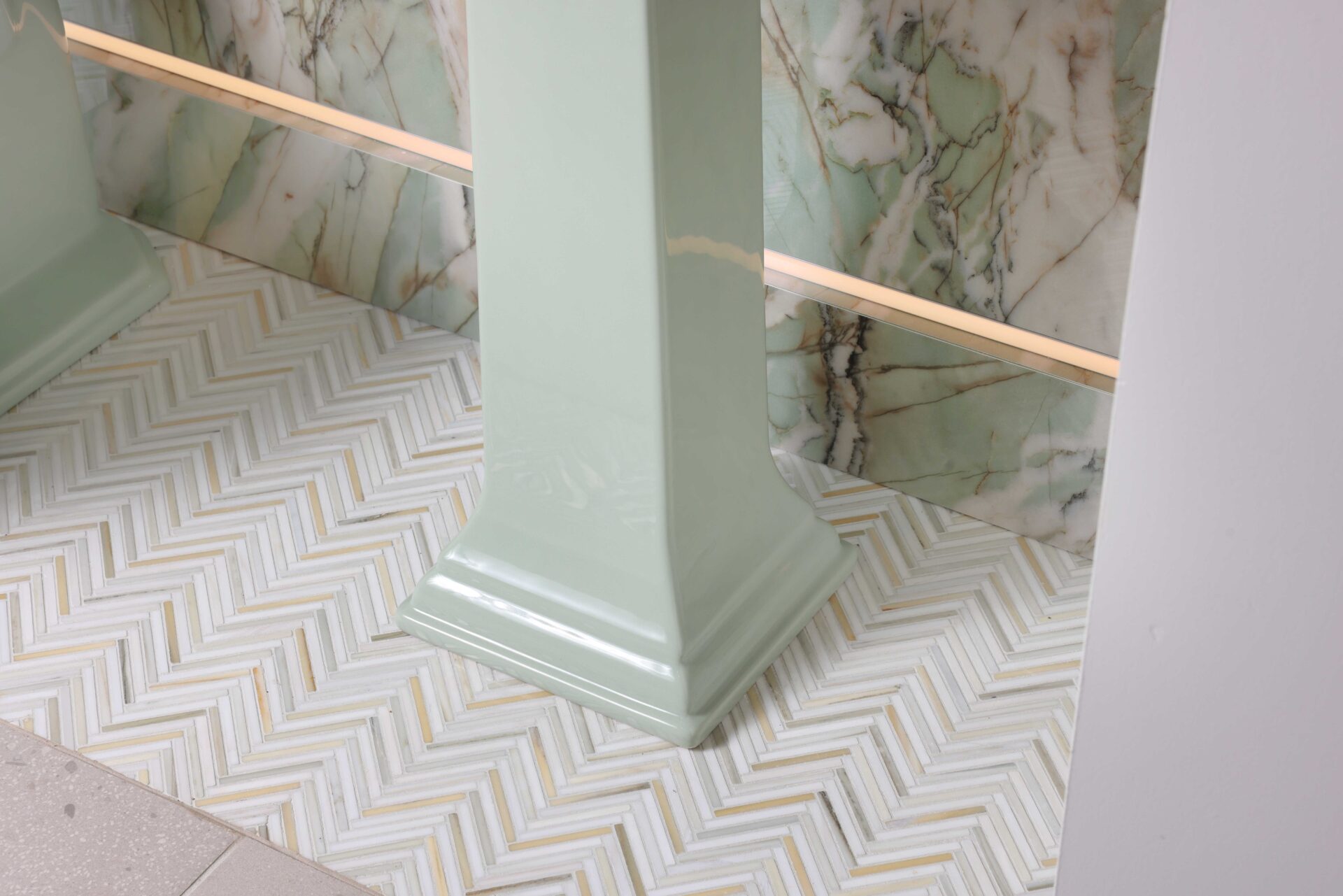 Marble floor tile in herringbone pattern in green powder room, porcelain feature wall with integrated LED lighting