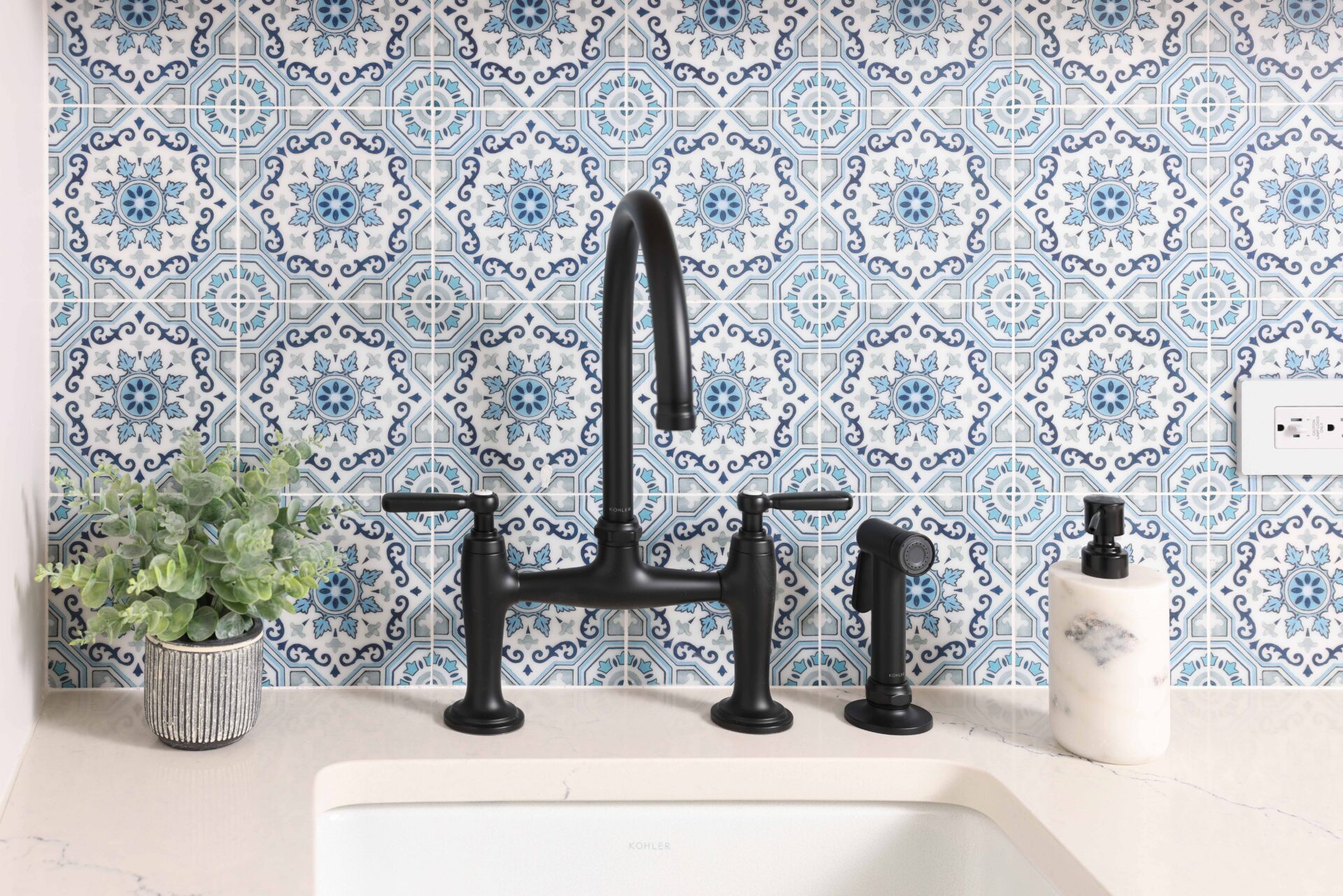 Matte black bridge faucet and patterned blue tile backsplash