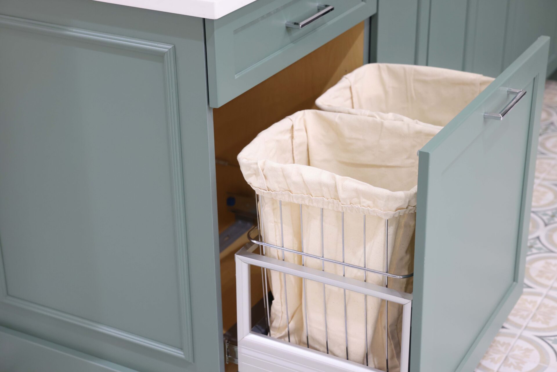 Double hamper drawer in green cabinet laundry room with decorative cabinet molding