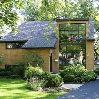 Modern home exterior featuring a wall of windows and a butterfly roof