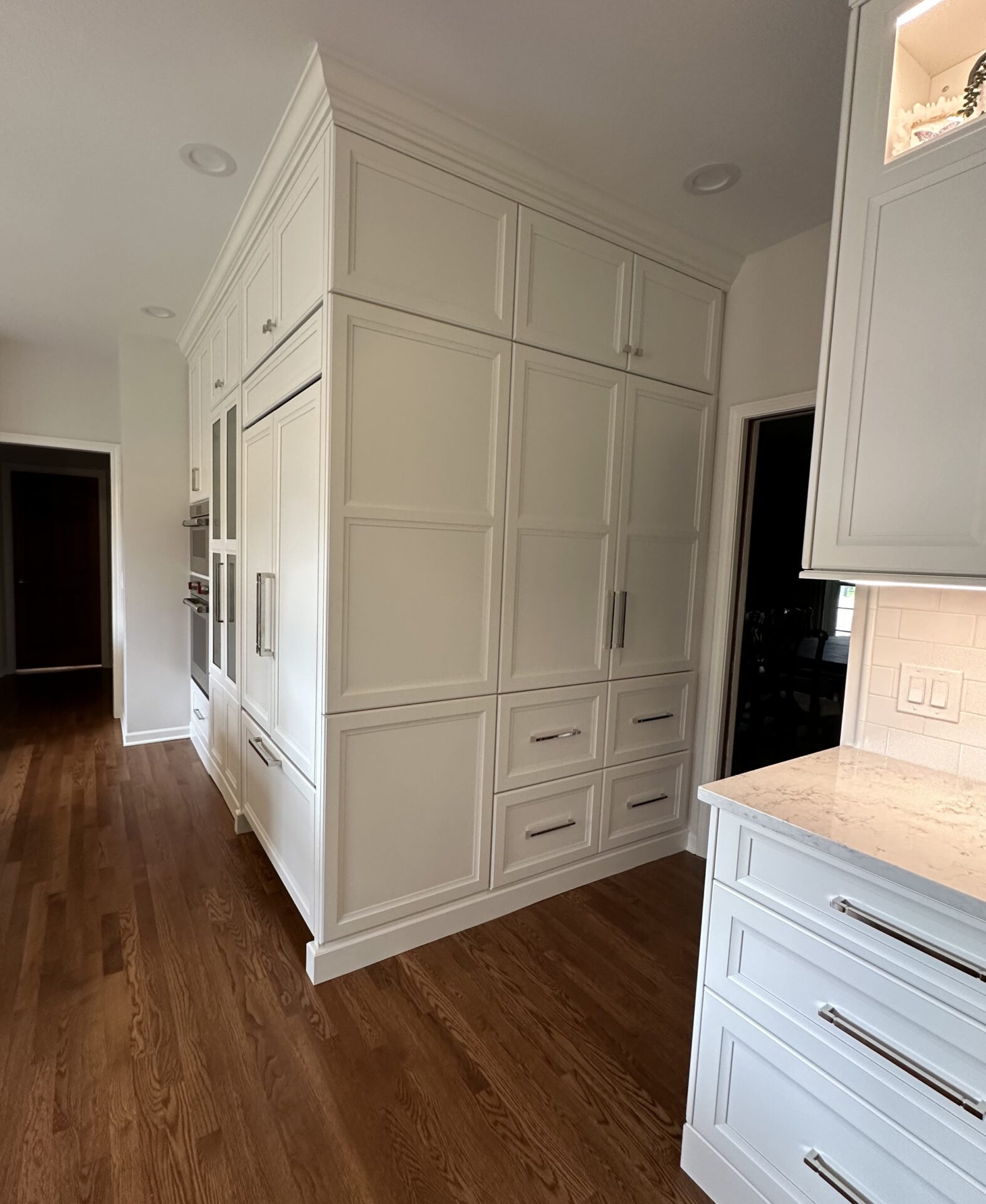 White kitchen with paneled refrigerator and cabinetry, stacked cabinets, glass paneled stacked cabinet