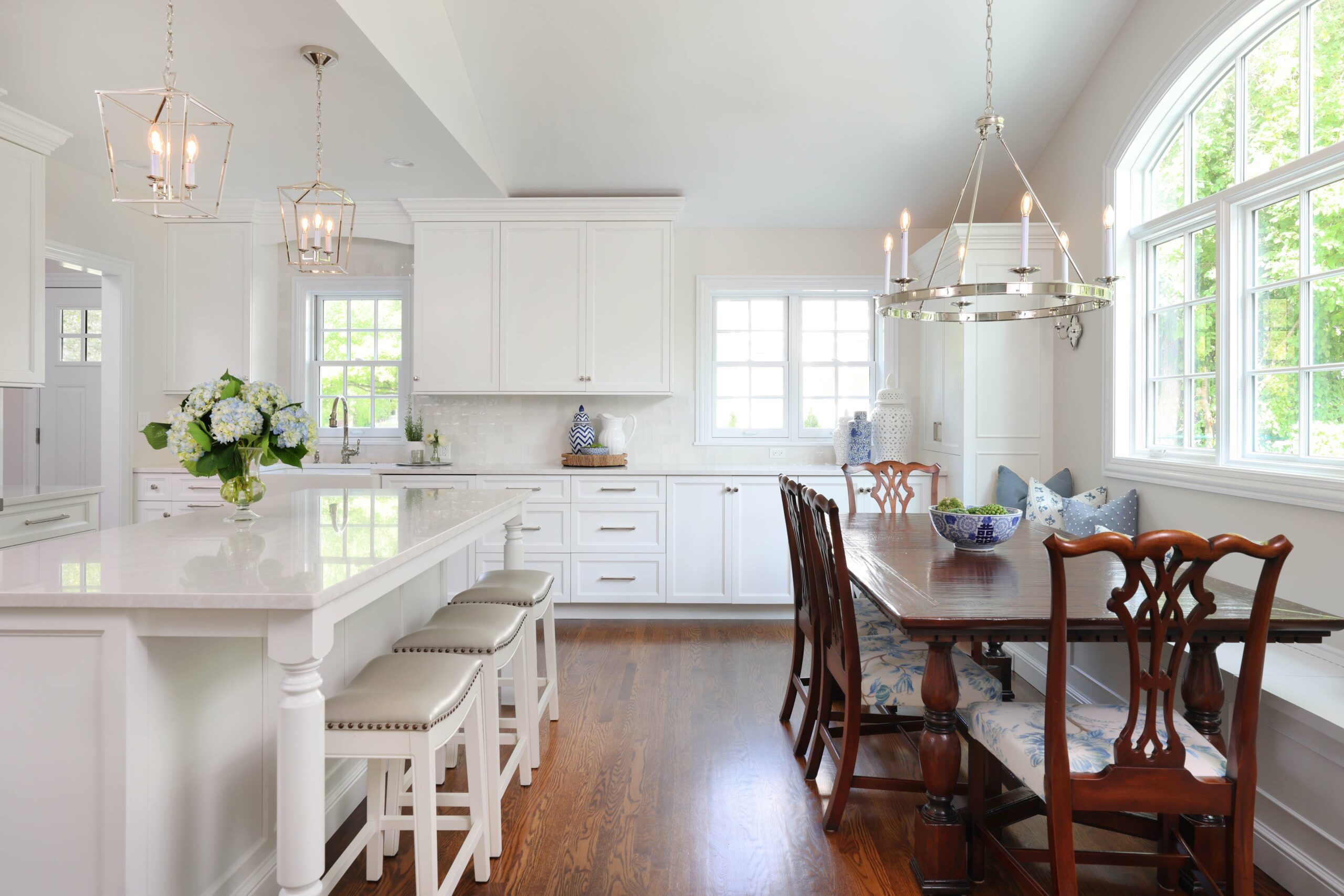 white kitchen addition with large island and stools and dining table with window bench seating
