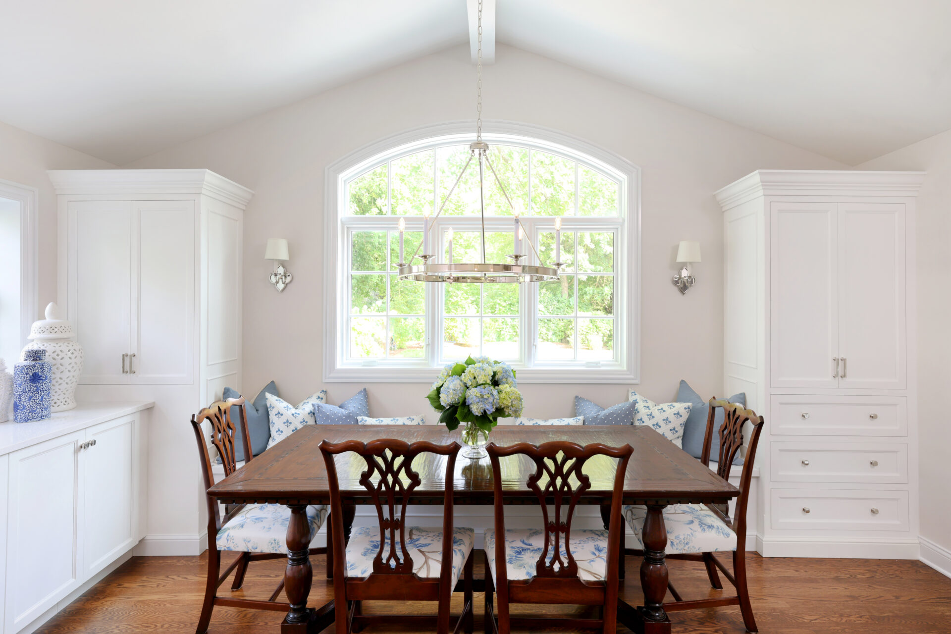White vaulted ceiling in white kitchen, windows looking out in background, table in foreground