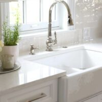 apron front kitchen sink and textured white backsplash