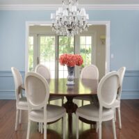 blue dining room with chandelier, wall moulding, hardwood floors