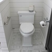 farmhouse style bathroom with grab bars near the toilet