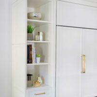 kitchen shelving and paneled fridge in white painted maple