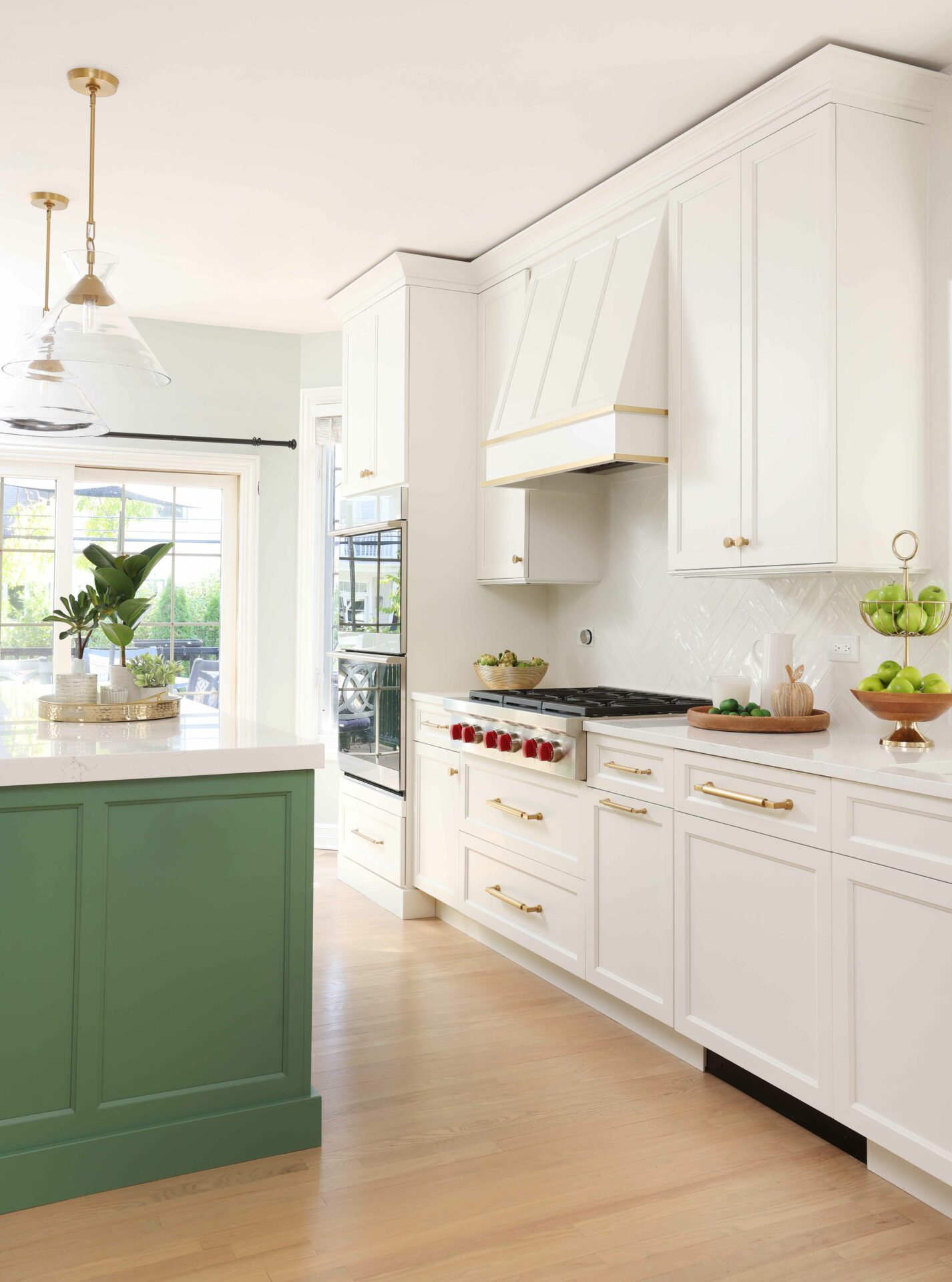 White kitchen with gold accents and green island cabinetry