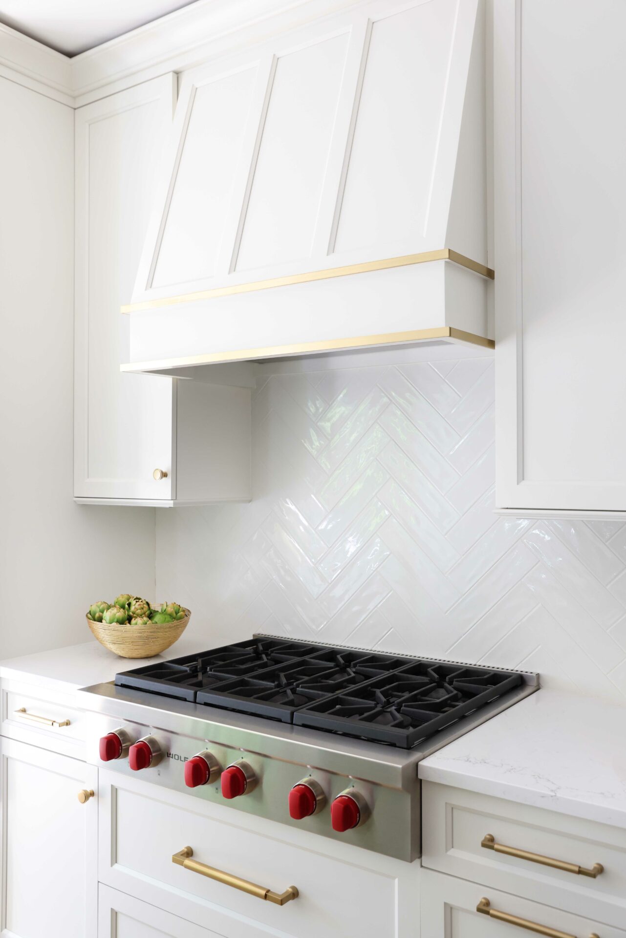 White cabinetry hood in the kitchen with gold accents