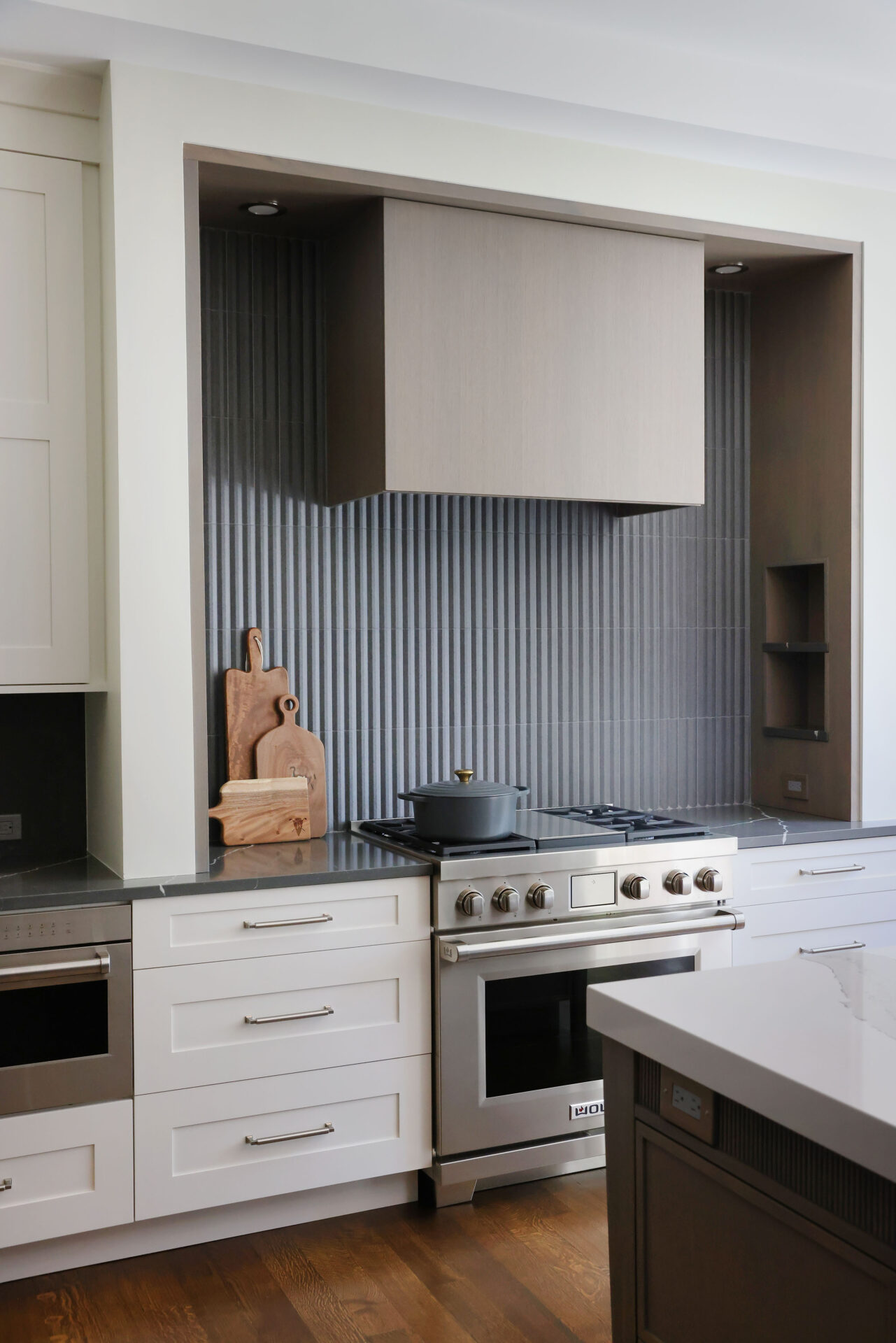Minimalist kitchen hood with textured vertical backsplash tile