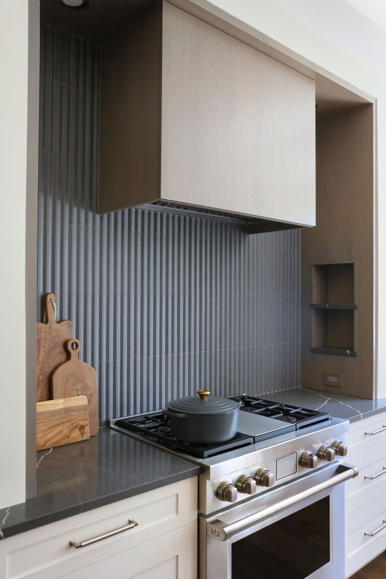 Kitchen range wall features clean line hood and storage niches