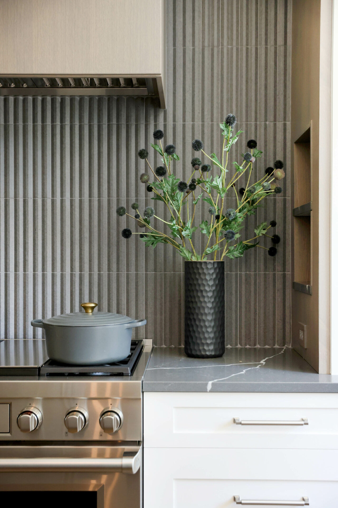 Dark gray vertical backsplash tile adds texture