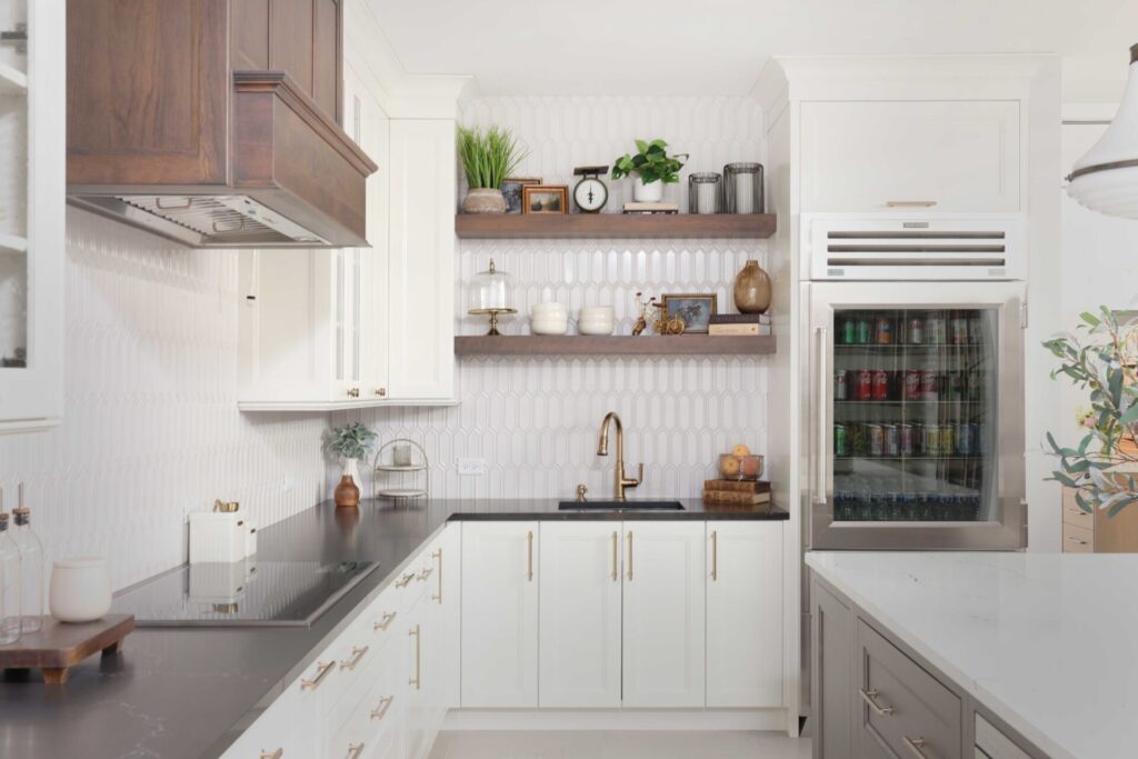 Vintage inspired family kitchen features cherry wood in the island, floating shelves and range hood; white picket backsplash tile, soft ivory painted cabinets with shaker style doors, black and white quartz countertops, pro grade induction cooktop, double ovens, below counter microwave, refrigerator with see-through door, black composite sink, faucet in luxe gold, mixed metal hardware throughout.