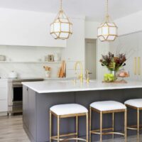 White modern kitchen with drywall hood, gold accents, and dark painted island