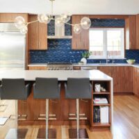 MCM wood stained kitchen with blue tile backsplash and island
