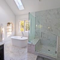 Primary bathroom with separate bathtub and shower featuring marble look tile