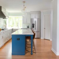 white kitchen with blue island and hall cabinet