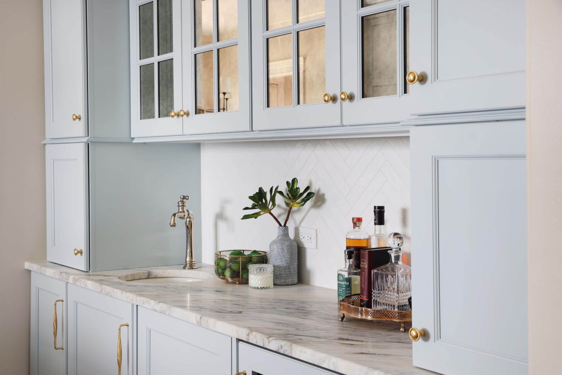 Wet bar with light blue cabinetry and antique mirror cabinet fronts